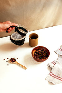 Pouring black coffee in a cup, and still scented coffee beans