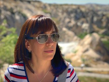 Woman wearing sunglasses against mountains