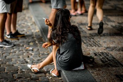 Rear view of people sitting on footpath