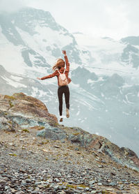 Jumping woman with backpack on mountain background. top of gornergrat, zermatt, swiss. alps hiking