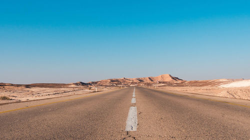 Road amidst desert against clear sky