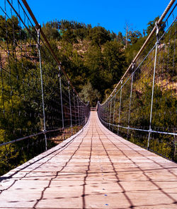 Footbridge amidst trees against sky