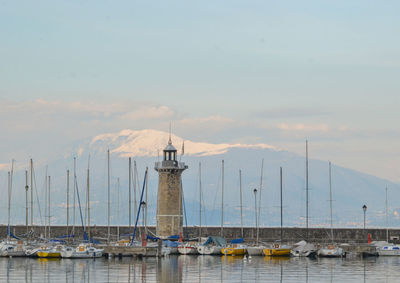 Sailboats moored in sea against sky during sunset