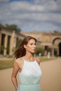 Portrait of young woman standing against building