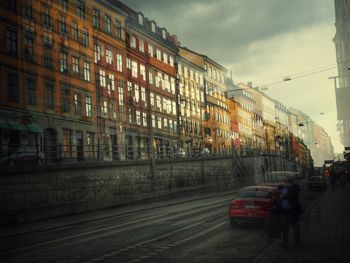 Cars on street by buildings in city against sky