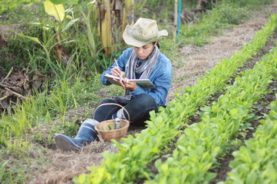 High angle view of farmer writing in diary at farm