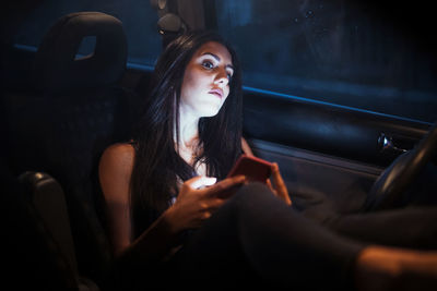 Young woman looking away while sitting in car