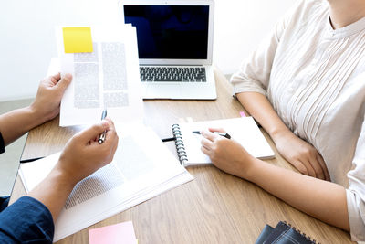 High angle view of people using laptop on table