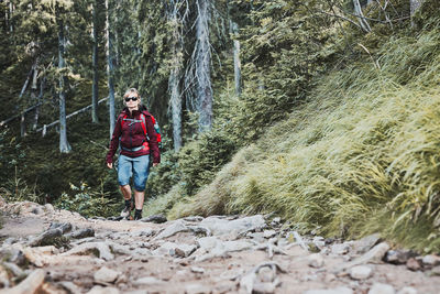 Woman with backpack hiking in mountains, spending summer vacation close to nature