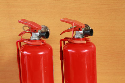 Close-up of fire extinguishers against wooden wall