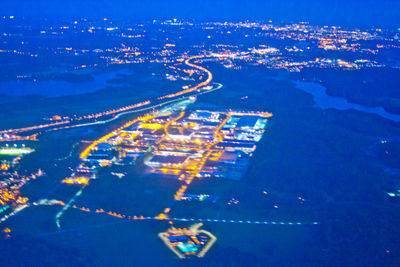 High angle view of illuminated city by sea against sky