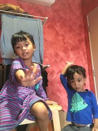 Portrait of girl showing stop gesture by brother at home