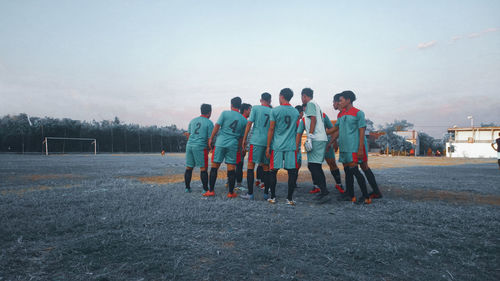 People standing on field against sky