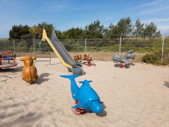 View of playground against trees on sunny day