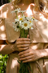 Midsection of woman holding flower outdoors