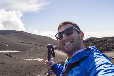 Portrait of happy male hiker standing at mt etna against sky