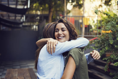 Affectionate mature women embracing at sidewalk cafe