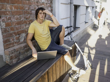 Puzzled man sits with laptop in street cafe. freelancer.student learns remotely from outdoors.