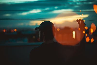 Silhouette man by sea against sky during sunset