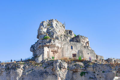 Low angle view of rock formations against clear blue sky