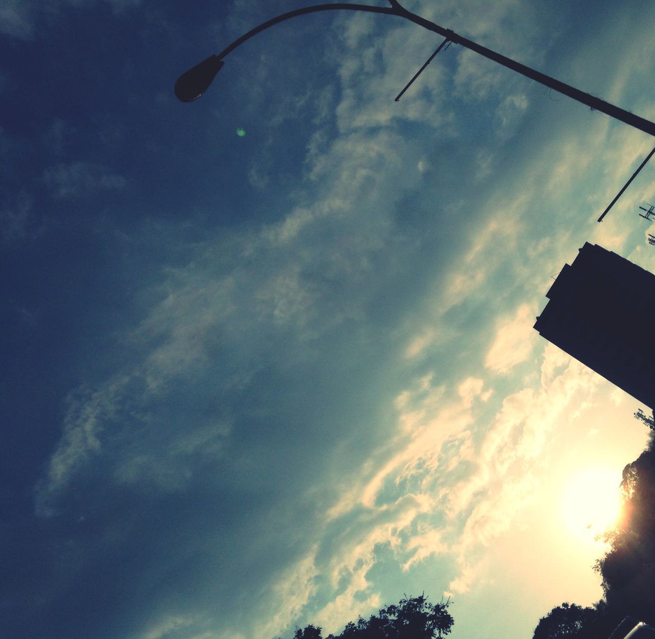 sky, low angle view, cloud - sky, building exterior, built structure, architecture, silhouette, cloud, cloudy, sunset, sunlight, building, outdoors, street light, no people, nature, dusk, city, day, sun