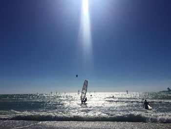People windsurfing on sea against sky on sunny day