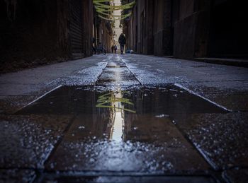 Wet alley amidst buildings in city during rainy season