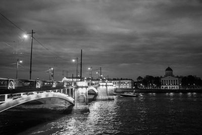 Illuminated birzhevoy bridge over malaya neva river against cloudy sky