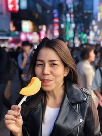 Portrait of woman holding ice cream in city