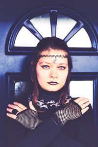 Portrait of young woman standing against wall