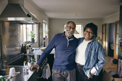 Portrait of happy senior couple standing with each other in kitchen at home