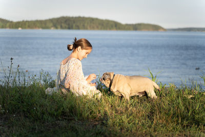 A girl and a pug on the lake shore