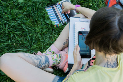 Full length of young woman sketching on book while sitting at park