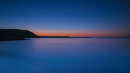 Scenic view of sea against clear sky at sunset