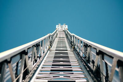 Low angle view of crane against clear blue sky