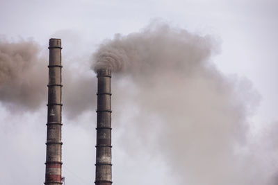 Smoke emitting from chimney against sky