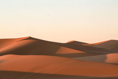 Scenic view of desert against clear sky during sunset