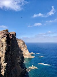 Rock formation in sea against blue sky