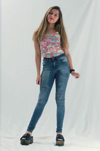 Portrait of young woman standing against white wall