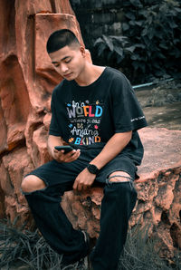 Young man sitting on rock