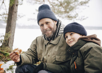 Smiling mature man having hot dog with son during winter
