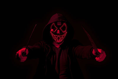 Portrait of man wearing mask against black background