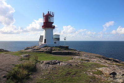 Lighthouse on shore against cloudy sky