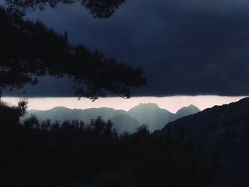 Silhouette trees and mountains against sky during sunset