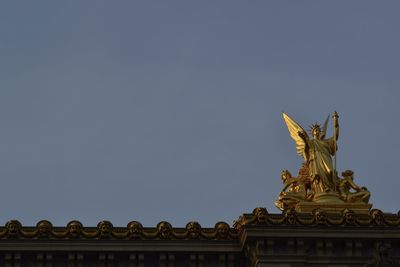 Low angle view of angel sculpture against clear sky at dusk