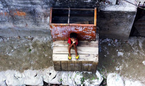 High angle portrait of boy sitting on wood