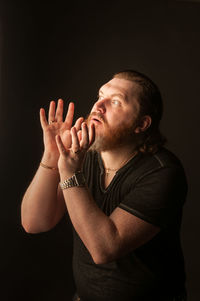 Young man looking away against black background