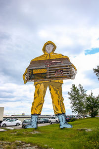 Low angle view of person standing by yellow car against sky