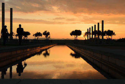 Silhouette trees by lake against sky during sunset