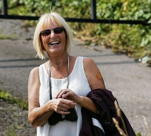 Portrait of cheerful woman standing on footpath